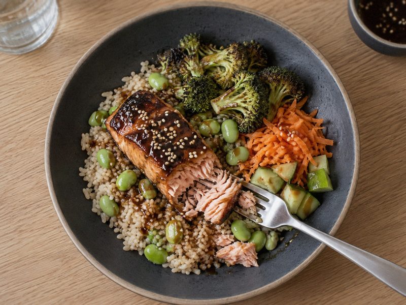 Teriyaki laks bowl med broccoli og brune ris på en mørk tallerken, set ovenfra